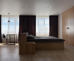 a bedroom with a bed and a table and windows at Поділля in Netishyn
