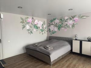 a bedroom with a bed with flowers on the wall at JK apartment in Rēzekne