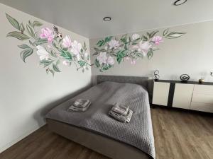 a bedroom with a bed with flowers on the wall at JK apartment in Rēzekne
