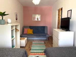 a living room with a blue couch and a tv at Lemuria Hostel Szkolna centrum in Legnica