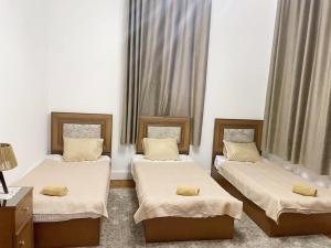 a room with three beds and a table with a lamp at Caretta in Cairo