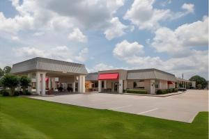 a large building with a red awning in a parking lot at Iberia House & Suites in New Iberia