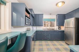 a blue kitchen with blue cabinets and a refrigerator at Private Riverside Retreat in Appleton