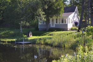 a white house with a pond in front of it at On Belanger Pond in Suttons Bay
