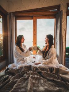 two women sitting on a bed in front of a window at Lush Atitlán in San Marcos La Laguna +60 photos