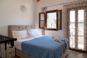 a bedroom with a bed with a blue blanket and two windows at Oceanis apartment in Symi