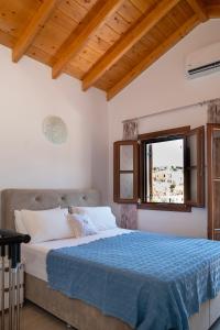 a bedroom with a bed with a blue comforter and a window at Oceanis apartment in Symi