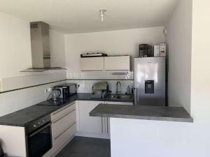 a kitchen with white cabinets and a refrigerator at Appartement Cosy in Le Crès