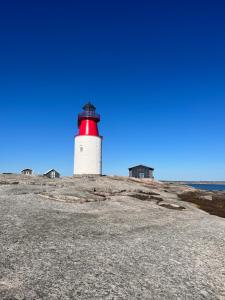 a red and white lighthouse on a rocky beach at Nyare lägenhet på Smögen, nära allt in Smögen
