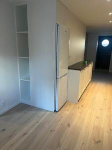 an empty room with a white refrigerator and a wooden floor at Nyare lägenhet på Smögen, nära allt in Smögen