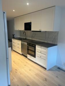 a kitchen with white cabinets and a black counter top at Nyare lägenhet på Smögen, nära allt in Smögen