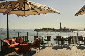 a woman sitting at a table on a deck near the water at Hotel Gabrielli Venezia - Starhotels Collezione in Venice