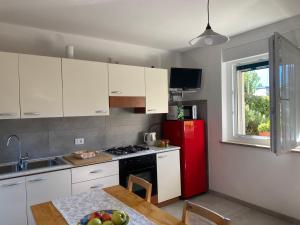 eine Küche mit weißen Schränken und einem roten Kühlschrank in der Unterkunft Casa Martello in Levico Terme