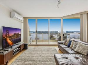 a living room with a large tv and large windows at 2-Bed Unit with Balcony BBQ & Stunning Lake Views in Belconnen