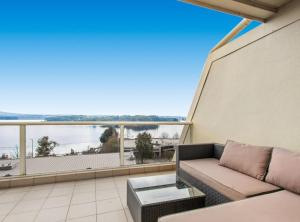 a couch on a balcony with a view of the water at 2-Bed Unit with Balcony BBQ & Stunning Lake Views in Belconnen
