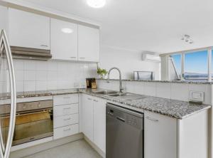 a white kitchen with a sink and a dishwasher at 2-Bed Unit with Balcony BBQ & Stunning Lake Views in Belconnen +6 photos