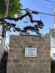 eine Statue eines Hundes auf einer Ziegelmauer mit einem Schild in der Unterkunft 25C - Pé na Areia do Tombo, 1 Suite Master, Ar Cond, 2Wc, 1 vaga, Roupa de Cama e Vivo fibra in Guarujá + 56 Fotos