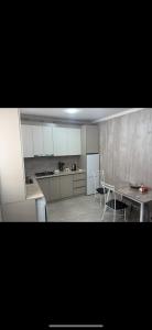 ギュムリにあるHyuratunの白いキャビネットとテーブルと椅子のあるキッチン