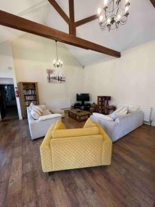 ein Wohnzimmer mit zwei Sofas und einem Kronleuchter in der Unterkunft The Old Hay Barn - Games Room, Gym, Sleeps 8 in Godmanchester