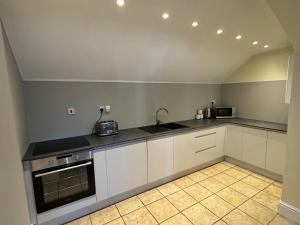 eine Küche mit weißen Schränken und einer Arbeitsplatte in der Unterkunft The Old Hay Barn - Games Room, Gym, Sleeps 8 in Godmanchester + 22 Fotos