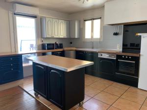 una cocina con armarios azules y una isla. en Chez Hughes, en Montaigut-sur-Save