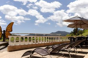 a group of chairs and an umbrella on a patio at Chalés São Francisco II in Santo Antônio do Pinhal
