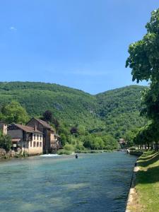 a river with houses and mountains in the background at Au Petit Casino in Vuillafans