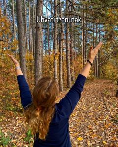 a woman standing in the woods with her arms in the air at Brvnare - Ranč Platan in Vrdnik