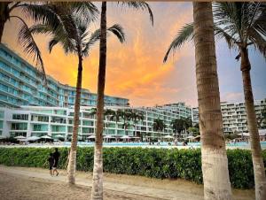 a group of palm trees in front of a hotel at Departamento Mike's in Nuevo Vallarta 
