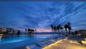 a swimming pool with chairs and palm trees at night at Departamento Mike's in Nuevo Vallarta  +9 photos
