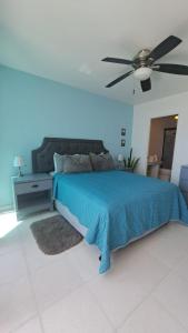 a bedroom with a blue bed and a ceiling fan at Departamento Mike's in Nuevo Vallarta 