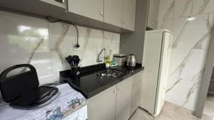 a small kitchen with a sink and a counter at Flat funcional e moderno em Uvaranas-com elevador in Ponta Grossa