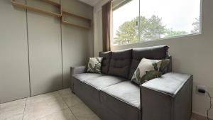 a leather couch in a room with a window at Flat funcional e moderno em Uvaranas-com elevador in Ponta Grossa