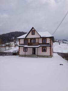 a house with snow on the ground in front of it at Гірська Домівка in Volosyanka
