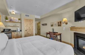 een slaapkamer met een groot wit bed en een open haard bij Penthouse Retreat Steps from the Gondola in Park West Ski Area Heliport +6 foto's