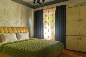 a bedroom with a bed with a green blanket and a window at Salcia Riverside Apartment in Galaţi