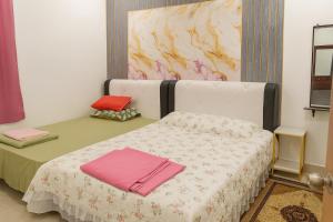Simpang EmpatにあるWelcome to MANAF HOME STAY, 3 Fully Furnished bedrooms, located in beautiful Alor Gajah, Melakaのベッドルーム1室(ピンクのタオルが付いたベッド1台付) +2枚の写真