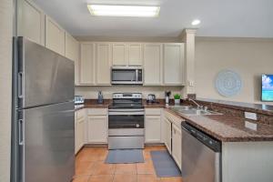 a kitchen with white cabinets and a stainless steel refrigerator at 2BR Condo with pool, near Disney! in Orlando +17 photos