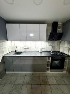 a kitchen with white cabinets and a sink and a stove at Простора і сучасна євродвушка в центрі Черкас! in Cherkasy