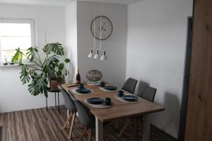 a dining room table with chairs and a clock on the wall at Heavens Wink in Emmerich