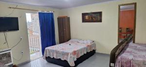 a bedroom with a bed and a balcony with a television at Hospedagem da Fran in Brasília