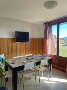 une salle à manger avec une table avec des chaises et une télévision dans l'établissement Carols cosy, à Font-Romeu-Odeillo-Via