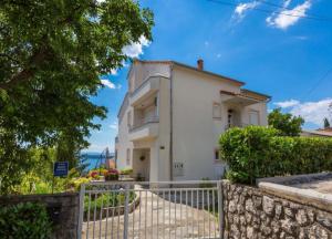 a white house with a fence in front of it at Apartmani Vanessa in Dramalj