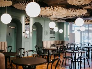 a dining room with tables and chairs and lights at ibis Styles Graz Messe in Graz