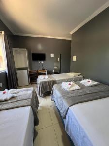 Una habitación de hotel con tres camas y un televisor de pantalla plana. en Pousada Praia Bela, en Maragogi