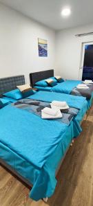 two beds in a room with blue sheets at Apartmani Toki Balkana in Mrkonjić Grad