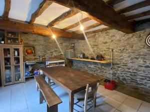 a kitchen with a wooden table and a stone wall at Chalet Gure Xokoa à Melles in La Celle-sous-Gouzon