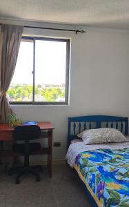 a bedroom with a bed and a desk and a window at Habitación privada en departamento compartido central in Chillán
