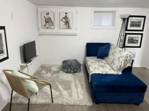 Una sala de estar con un sofá azul y un televisor en Merritt Place Niagara, en St. Catharines