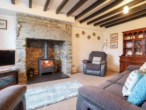a living room with a stone fireplace and a chair at Bryn Re in Trawsfynydd